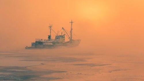 Ship in sea at sunset