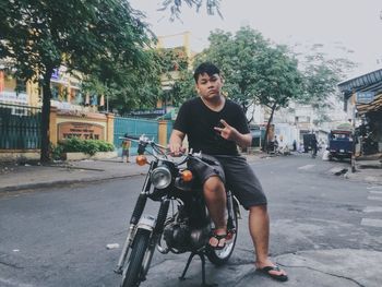 Portrait of young man sitting on street in city