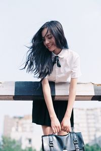 Full length of young woman standing against wall