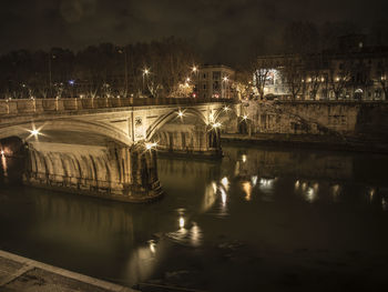 River by illuminated city against sky at night