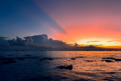 Scenic view of sea against dramatic sky during sunset