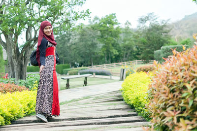 Portrait of smiling woman in hijab standing at park