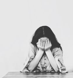 Portrait of woman covering face against white background