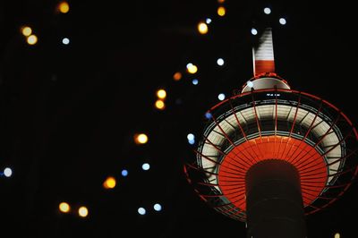 Low angle view of illuminated christmas lights by kyoto tower at night