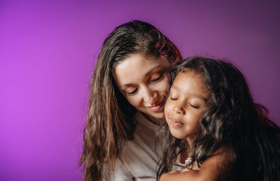 Portrait of mother and daughter against pink background