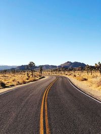 Road amidst landscape against clear blue sky