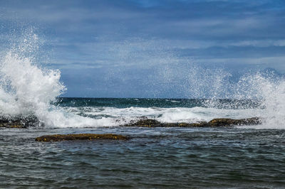 Waves splashing on sea against sky