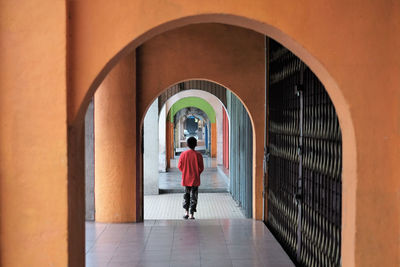 Rear view of boy walking in corridor of building