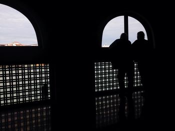 Silhouette built structure against sky seen through window