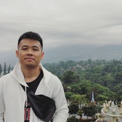 Portrait of young man standing against sky