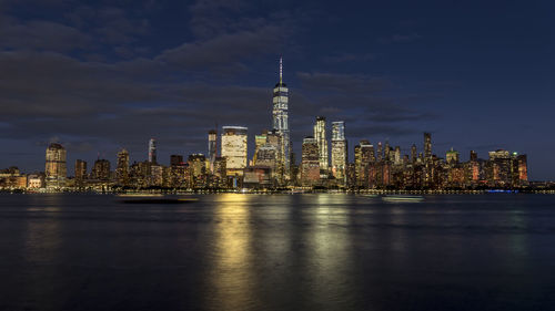 Illuminated buildings against cloudy sky
