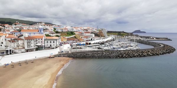 Aerial view of townscape by sea against sky