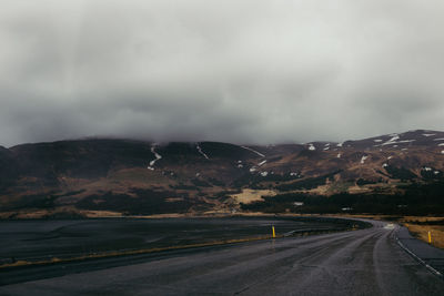 Country road against cloudy sky