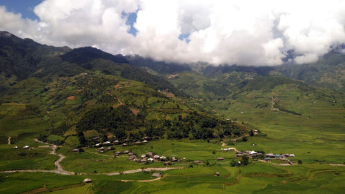 Scenic view of green landscape and mountains against sky