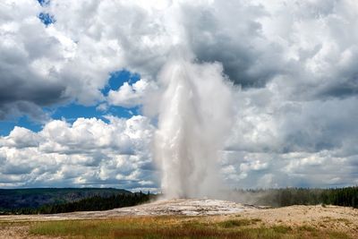 Geyser spraying against cloudy sky