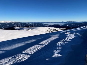 Snow covered landscape against blue sky