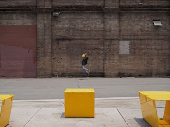 Side view of boy jumping on road against wall