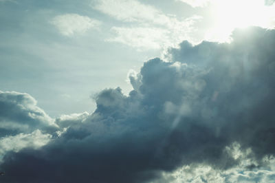 Low angle view of sunlight streaming through clouds