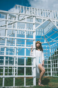 Portrait of smiling young woman standing against built structure