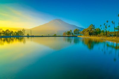 Scenic view of lake and mountains against blue sky