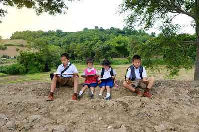 People sitting on land against trees