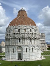 View of pisa baptistery and the leaning tower building against cloudy sky