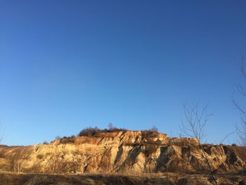 Rock formations on landscape against clear blue sky