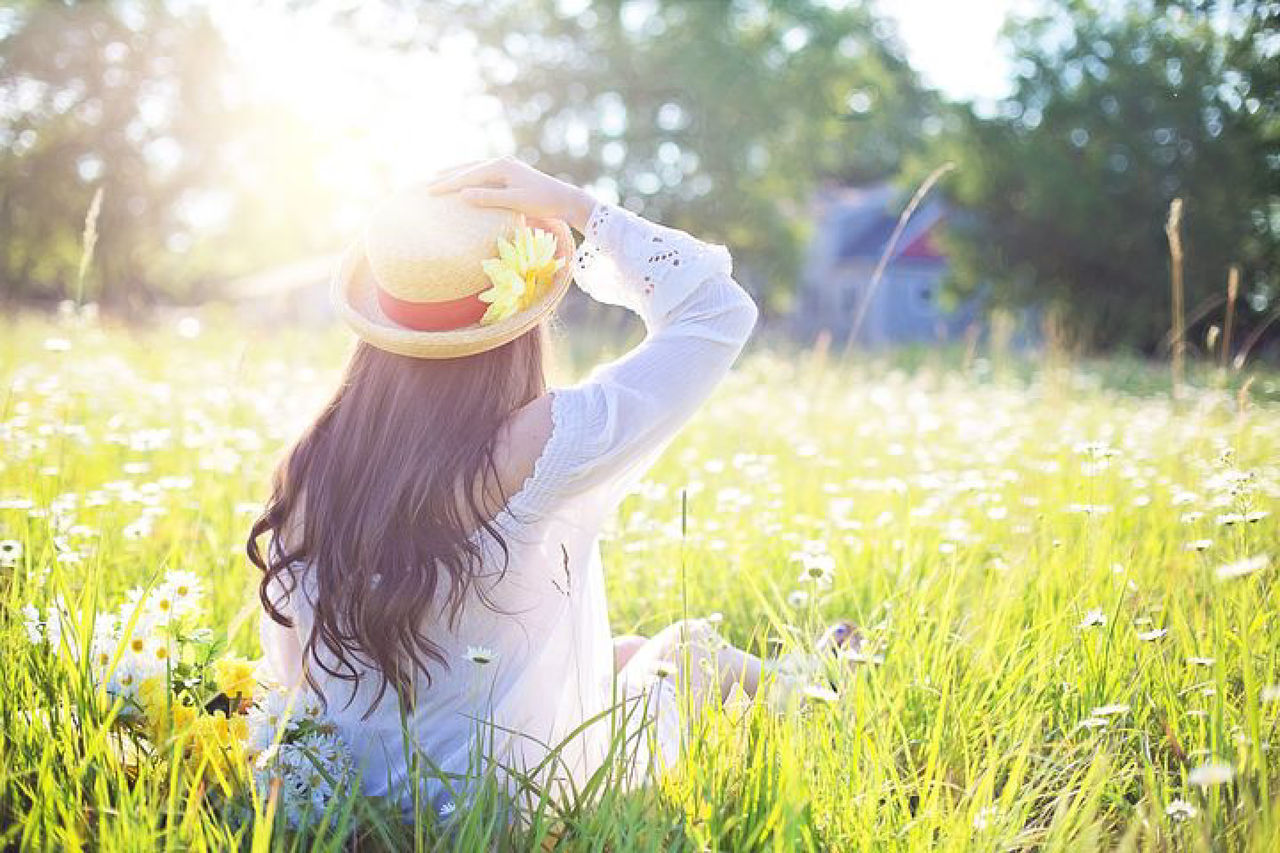 WOMAN WITH FLOWERS ON FIELD IN BACKGROUND