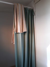 Low angle view of striped towel hanging on shower curtain rod at home with pale green curtain