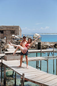 Man carrying woman on pier over sea