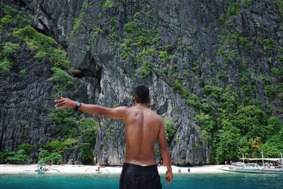 Rear view of shirtless man in swimming pool against trees