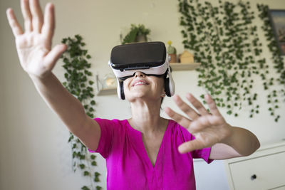 Woman gesturing while enjoying virtual reality through headset at home