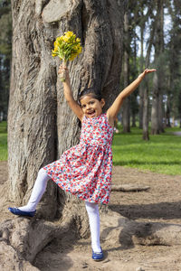 Full length portrait of cute girl standing by tree