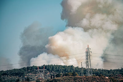 Smoke emitting from electricity pylon against sky