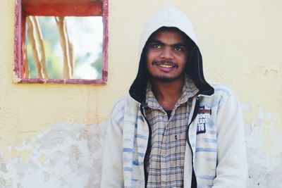 Portrait of young man standing against wall