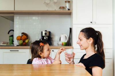 Woman and girl having food at home