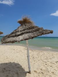 Thatched roof on beach against sky