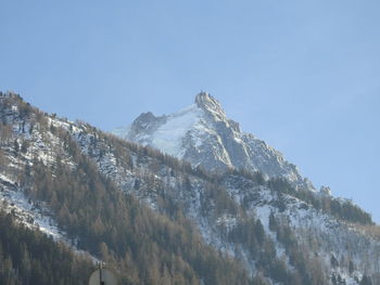 Low angle view of snowcapped mountains against clear sky