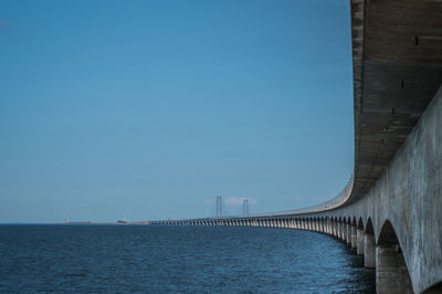 Bridge over sea against clear blue sky