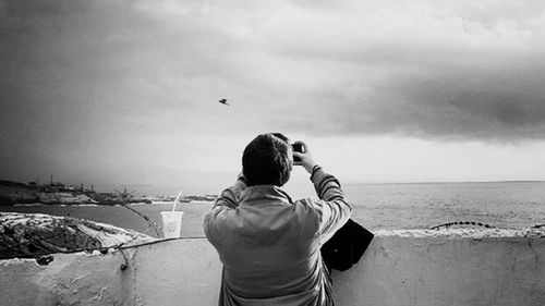 Rear view of man photographing sea