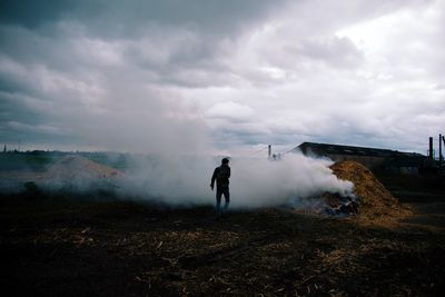 Rear view of man standing on land against sky