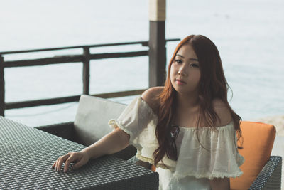 Portrait of beautiful young woman against sea