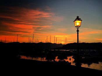 Illuminated street light against sky during sunset