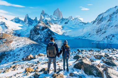 Rear view of people standing on snowcapped mountain