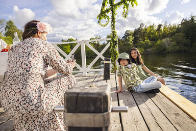 Mother photographing children sitting under midsummer maypole