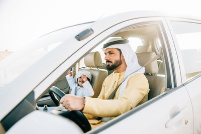 Father and son sitting in car at desert