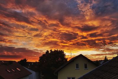 Houses and buildings against dramatic sky during sunset