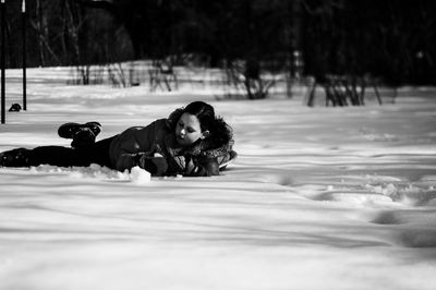 Side view of girl lying on snow covered field