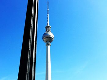 Low angle view of communications tower against blue sky