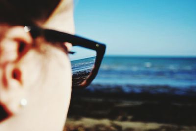 Close-up of man photographing sea against clear sky